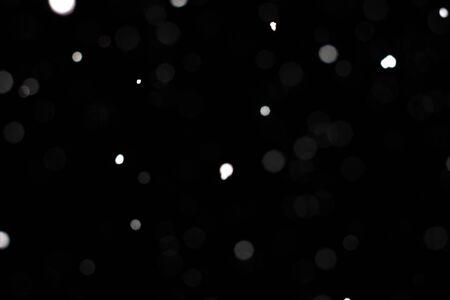 Freeze motion of white powder coming down, isolated on black, dark background. Abstract design of falling dust cloud. Particles cloud screen saver, wallpaper with copy space. Rain, snow fall conceptの写真素材