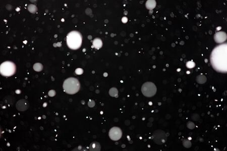 Freeze motion of white powder coming down, isolated on black, dark background. Abstract design of falling dust cloud. Particles cloud screen saver, wallpaper with copy space. Rain, snow fall conceptの写真素材
