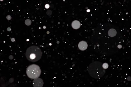 Freeze motion of white powder coming down, isolated on black, dark background. Abstract design of falling dust cloud. Particles cloud screen saver, wallpaper with copy space. Rain, snow fall conceptの写真素材