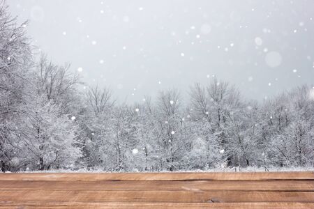 Wooden table on the background of the winter forest. Blank for winter advertising. Empty the table on backdrop of forests, place on the writing.の写真素材