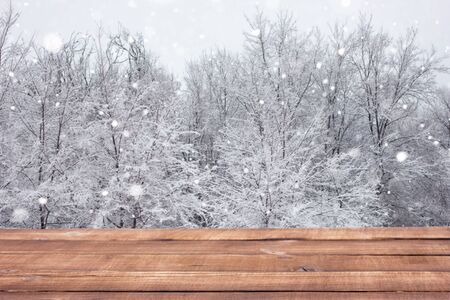 Wooden table on the background of the winter forest. Blank for winter advertising. Empty the table on backdrop of forests, place on the writing.の写真素材