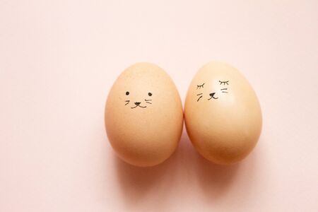two eggs with smiles on a pink pastel background, a concept with Easter eggs for Easter. Egg huntの写真素材