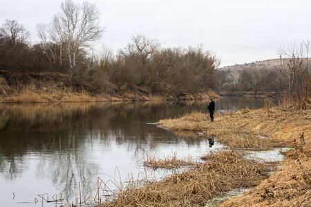 a man is fishing on the river in late autumn. Hiking in the wild, campingの写真素材