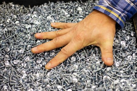 a man buys self-tapping screws in a supermarket at retail, a choice of self-tapping screws, self-service in the storeの写真素材