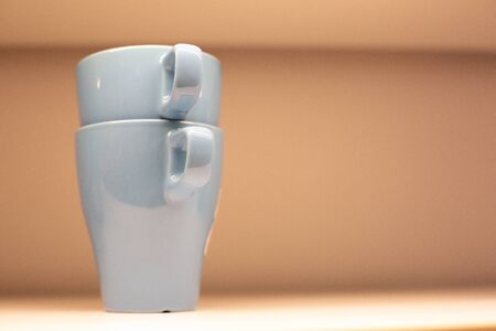 two blue cups on a delicate background with a place for an inscription. Two mugs closeup on a beige backgroundの写真素材