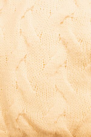 texture of a knitted sweater in beige color, closeup. Soft, light clothesの写真素材