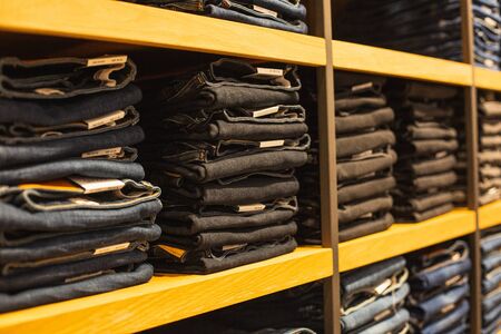shelf with denim pants for sale in a boutique. A closet with a group of classic zhidinsymi pants, close-upの写真素材