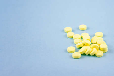 many round yellow pills for the treatment of diseases and prevention on a blue background. With place for textの写真素材