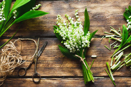 cooked delicate bouquet of fresh lilies of the valley on a wooden dark background.の写真素材