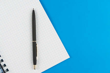 School notebook in a box with a black pen on a blue background. View from above. Place for text.の写真素材