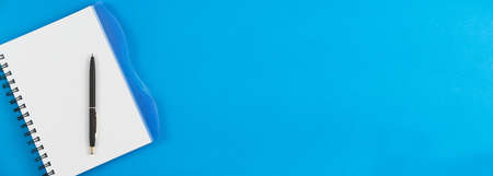 Notebook in a box with a black pen on a blue background. Place for text. Photo banner.の写真素材