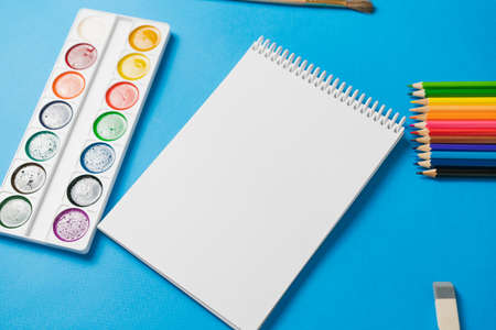 Bound notebook and colorful school supplies on a blue background. View from above. Place for text.の写真素材