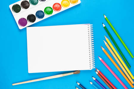 Bound notebook and colorful school supplies on a blue background. View from above. Place for text.の写真素材