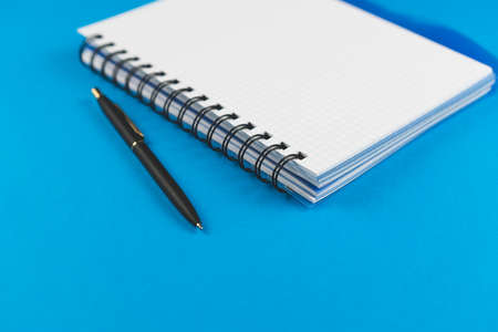 Checkered notebook with a black pen on a blue background. Place for text.の写真素材