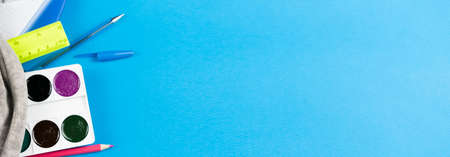 The contents of the school gray portfolio are stationery such as watercolors, pens, crayons and stickers, ruler, notepad, shavings on a blue background. Place for text.の写真素材