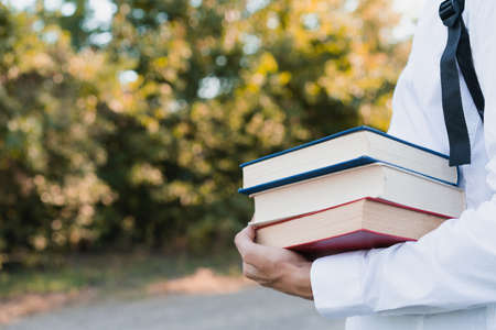 A guy in a classic white shirt holds a stack of books with one hand with space for an inscription, education concept. Photo banner.の写真素材