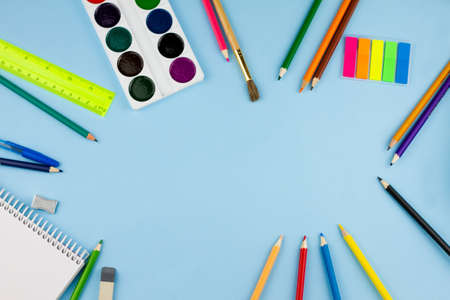 Scattered colorful school supplies on a light blue background. Place for text. View from above.の写真素材