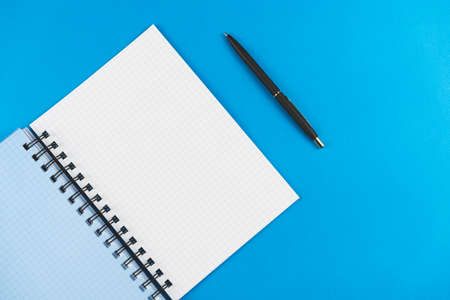 Checkered notebook with a black pen on a blue background. Place for text.の写真素材