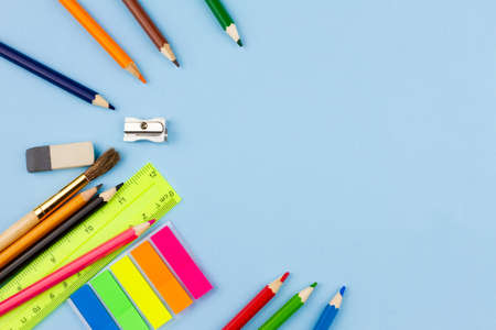 Multicolored school supplies scattered in a semicircle on a blue background. View from above. Place for your text.の写真素材