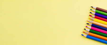 Colored saturated pencils for drawing on a yellow background. Photo banner. Place for your text. View from above.の写真素材