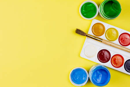 Various colored paints for painting on a yellow background. Place for your text. View from above. Education concept.の写真素材