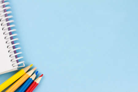 White blank notebook with colored pencils on a blue background. Place for your text. View from above. Education concept.の写真素材