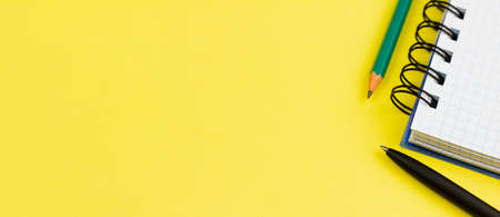 Blank white notebook with a black pen and pencil on a yellow background. Photo banner. View from above. Place for your text.の写真素材