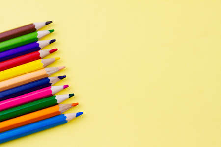 Colored saturated pencils for drawing on a yellow background. Place for your text. View from above. Education concept.の写真素材