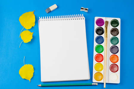 Blank notebook with watercolors on a light blue background. View from above. Place for your text. Education concept.の写真素材