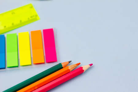 Colored stickers and pencils on a blue background. View from above. Place for your text. Education concept.の写真素材