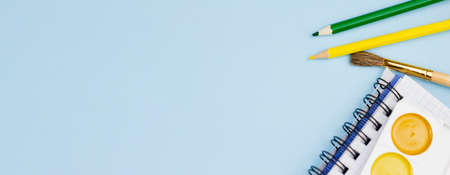 Paint with notepad on a blue background. Photo banner. Place for your text. Education concept.の写真素材