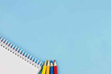 White blank notebook with colored pencils on a blue background. Place for your text. View from above. Education concept.の写真素材
