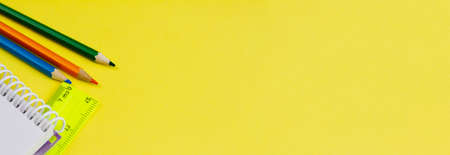 Blank notebook with colored pencils on a yellow background. Photo banner. Place for your text. View from above. Education concept.の写真素材