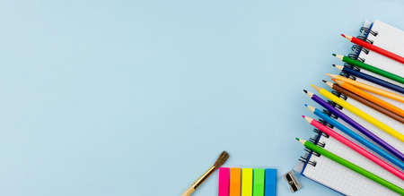Colored pencils lie on a notebook on a blue background. Photo banner. Place for your text. Education concept.の写真素材