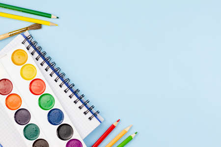 Watercolor lies on a notebook with pencils on a blue background. Place for your text. Education concept.の写真素材
