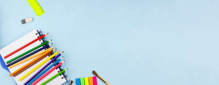 Colored pencils lie on a notebook on a blue background. Place for your text. Education concept.の写真素材