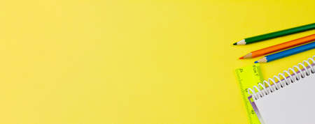 Blank notebook with colored pencils on a yellow background. Photo banner. Place for your text. View from above. Education concept.の写真素材