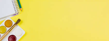 White notebook with paints on a yellow background. Photo banner. Place for your text. Education concept.の写真素材
