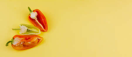 three cut multi-colored ripe peppers on a pastel yellow background with space for text, photo banner. The concept of vegetarianismの写真素材