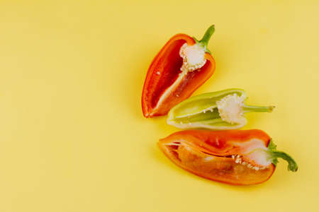 three cut multi-colored ripe peppers on a pastel yellow background, close-up. Healthy food conceptの写真素材