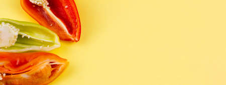 three cut multi-colored ripe peppers on a pastel yellow background with space for text, photo banner. The concept of vegetarianismの写真素材