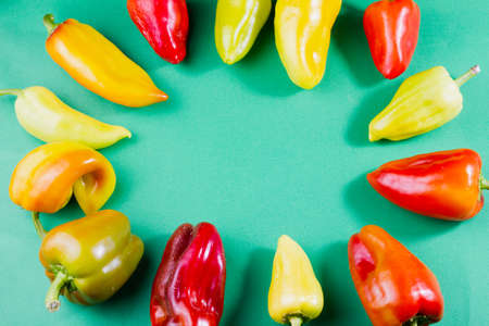 set of ripe assorted bell peppers on a pastel green background lie around, with an empty place in the center under the text, Asian natural vegetable backgroundの写真素材