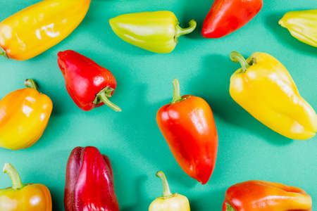 group of multi-colored ripe bell peppers lie on a pastel green background top view, food background, natural fresh products for vegetarian cuisineの写真素材
