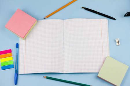 Notebook with different school supplies on a blue pastel background. View from above. Education concept.の写真素材