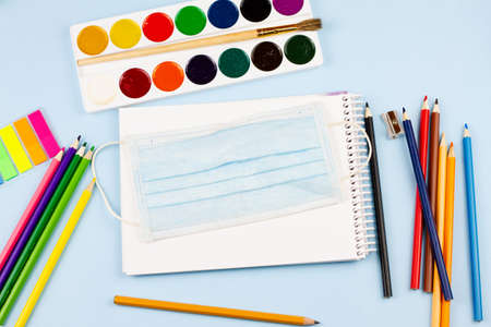 Essential school supplies with a mask on a blue background. The concept of education. View from above. Epidemic.の写真素材