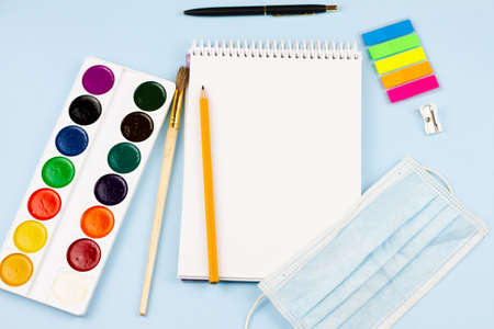 Essential school supplies with a mask on a blue background. The concept of education. View from above. Epidemic.の写真素材