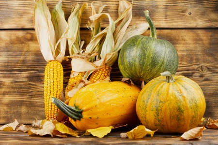 Yellow and green pumpkins with corn on a wooden background. Autumn harvest concept. Autumn still life.の写真素材