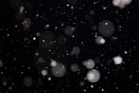 Freeze motion of white powder coming down, isolated on black, dark background. Abstract design of falling dust cloud. Particles cloud screen saver, wallpaper with copy space. Rain, snow fall conceptの写真素材