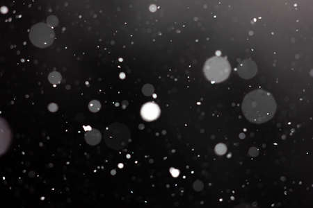 Freeze motion of white powder coming down, isolated on black, dark background. Abstract design of falling dust cloud. Particles cloud screen saver, wallpaper with copy space. Rain, snow fall conceptの写真素材