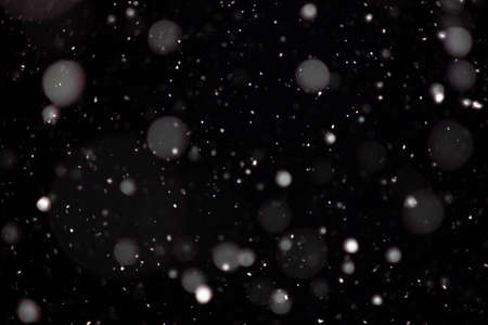 Freeze motion of white powder coming down, isolated on black, dark background. Abstract design of falling dust cloud. Particles cloud screen saver, wallpaper with copy space. Rain, snow fall conceptの写真素材